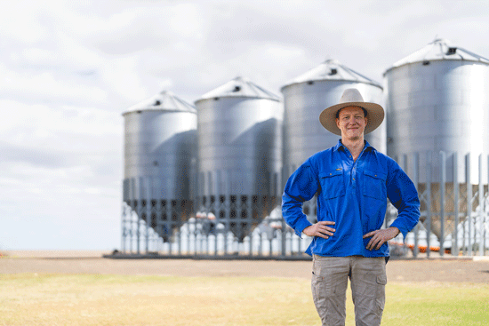 Felix Reinglben stands in front of four grain silos.
