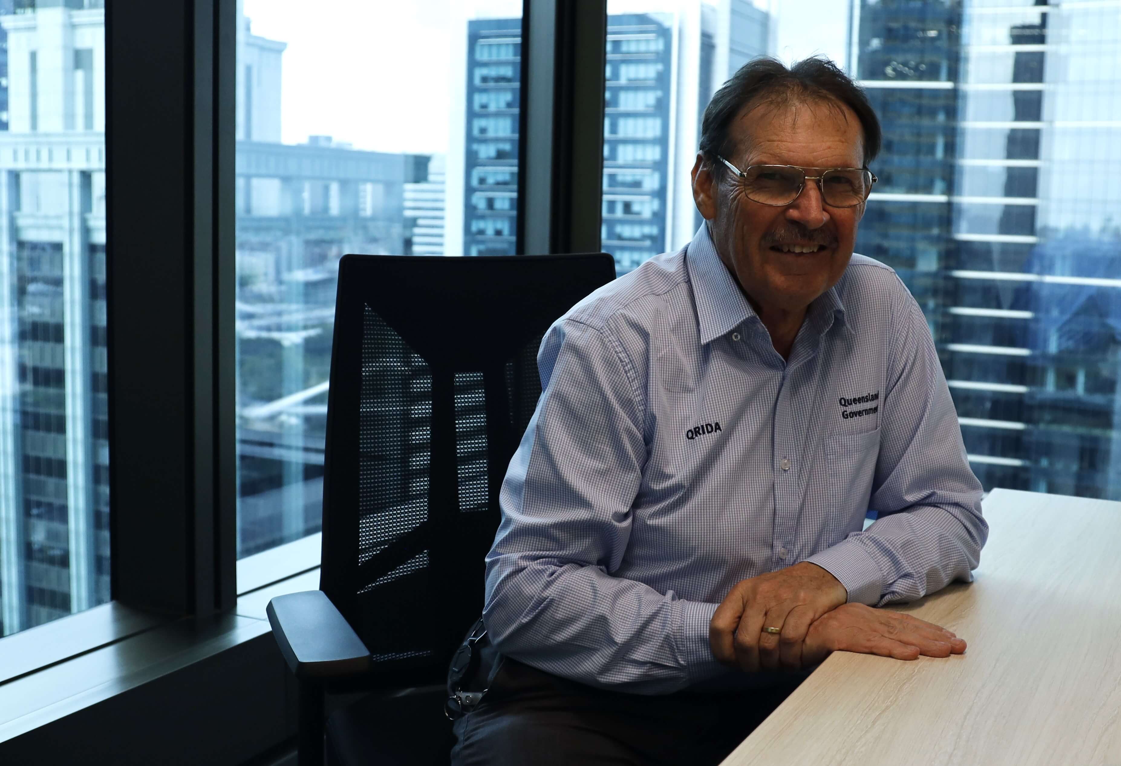 QRIDA's Economist John Gillespie sitting at a desk with city in the background