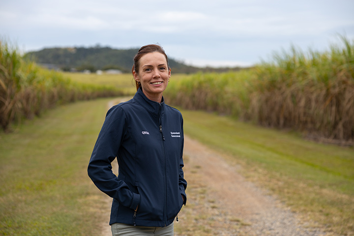 Tegan McBride standing in a driveway with sugarcane fields either side of her